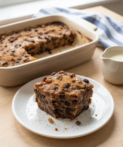 Slice of Delia Smith bread pudding on white plate with cream jug